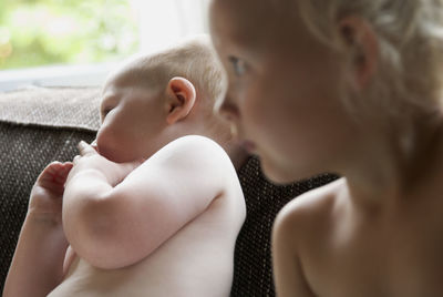 Close-up of siblings on sofa at home