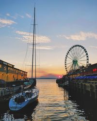 Sailboats moored in sea against sky at sunset