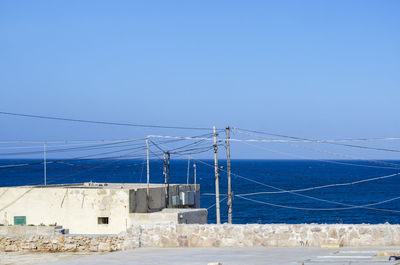 Bridge over sea against clear blue sky