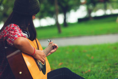 Woman playing guitar on field