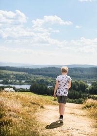 Rear view of boy standing on land against sky scotland hills roam 