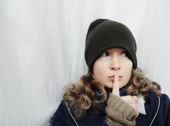 Portrait of woman in hat against wall