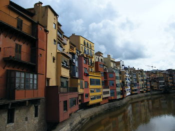 Low angle view of buildings by river against sky