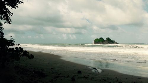 Scenic view of beach against cloudy sky