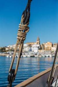 Close-up of rope tied to moored at harbor against clear sky