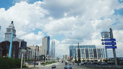 City street amidst buildings against cloudy sky