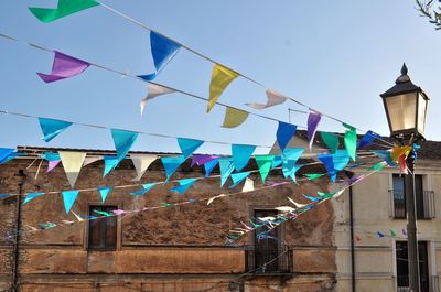 Low angle view of flags hanging against blue sky