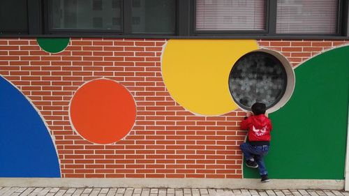 Boy standing against brick wall