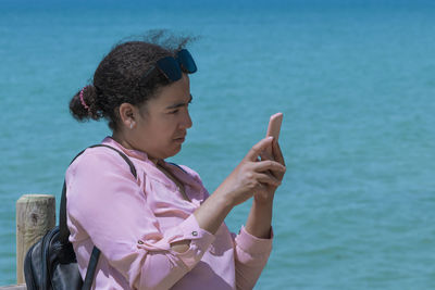 Side view of young woman using mobile phone