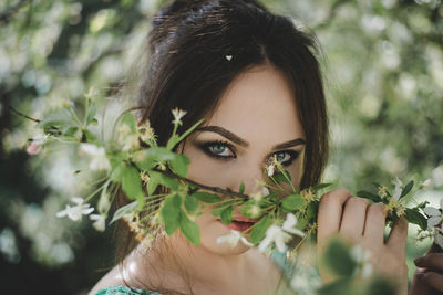 Portrait of beautiful young woman holding plants at park