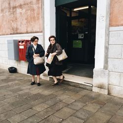 Full length of friends standing at entrance of building