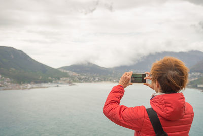 Rear view of woman photographing against sky