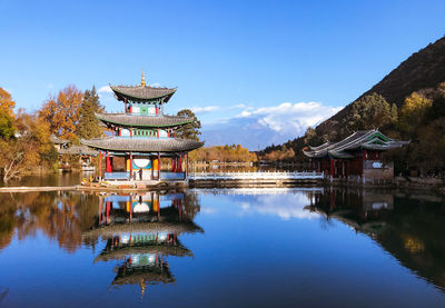 Gazebo in lake by building against blue sky