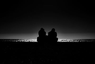 Silhouette couple on beach against clear sky