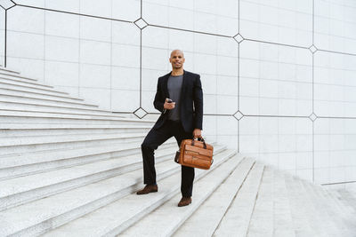 Full length of businessman standing against wall