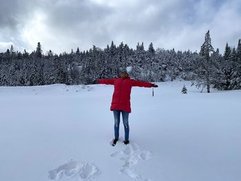 Rear view of person standing on snow covered field