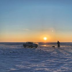 People on snow covered land during sunset