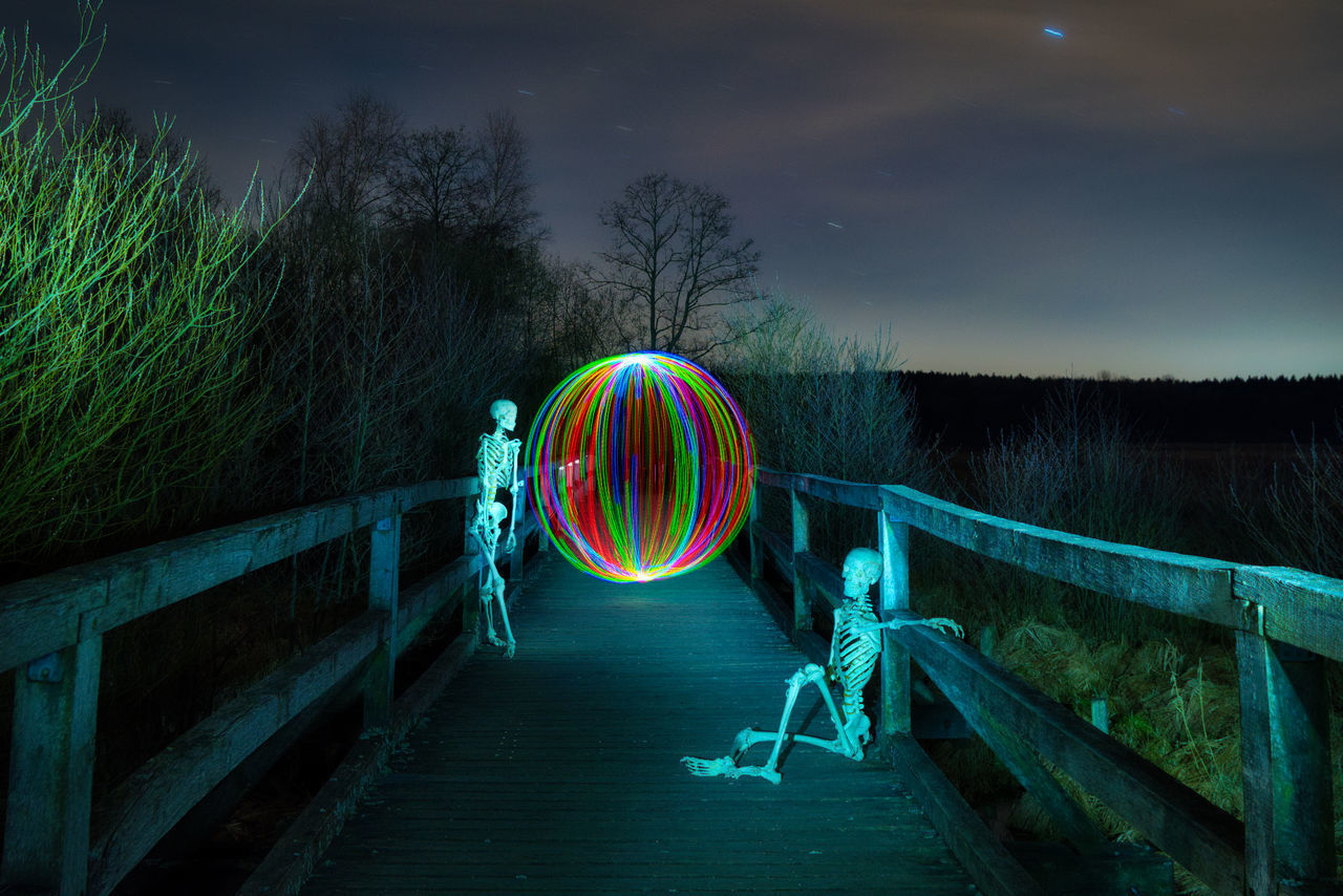 LIGHT PAINTING ON RAILING AGAINST SKY