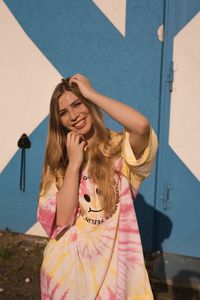 Portrait of smiling young woman standing against wall