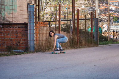 Full length of woman skateboarding on road in city