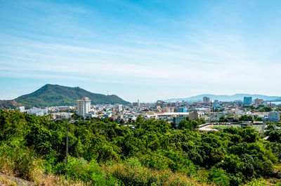 Trees and buildings in city against sky