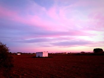 Buildings on field against sky during sunset