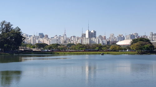 View of river in front of buildings against clear sky