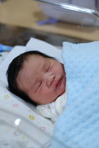 Close-up of cute baby boy lying on bed at home