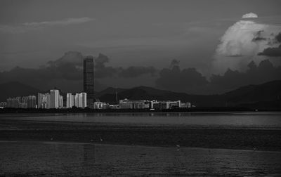 Smoke emitting from factory by sea against sky