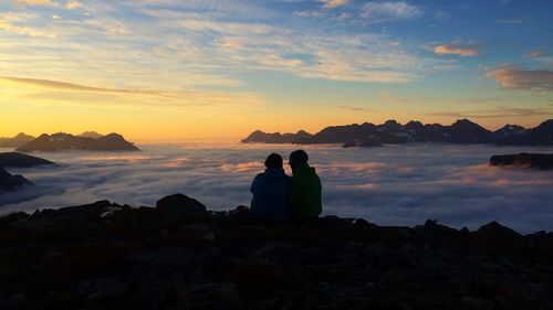 Rear view of people on mountain in foggy weather at hjorundfjord against sky