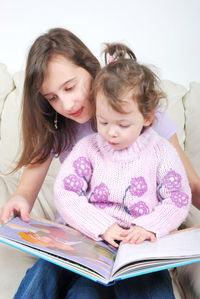 Sisters looking at book at home