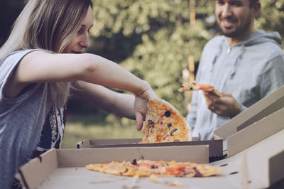 Young woman removing pizza from box