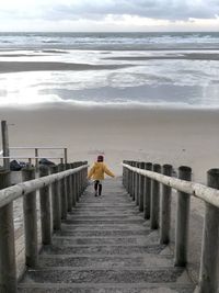 Rear view of girl moving down on steps at beach