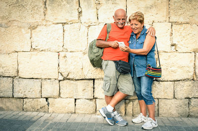 Portrait of happy friends standing against wall