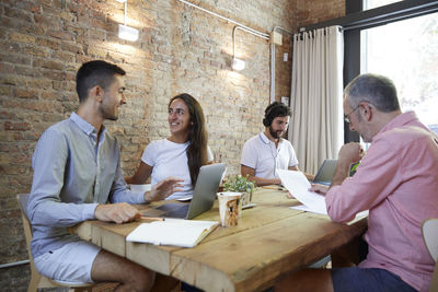 Male friends using laptop while sitting on table