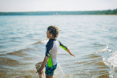 Caucasian boy running into water with splashes and laughter. vacation on sea side. happy childhood.