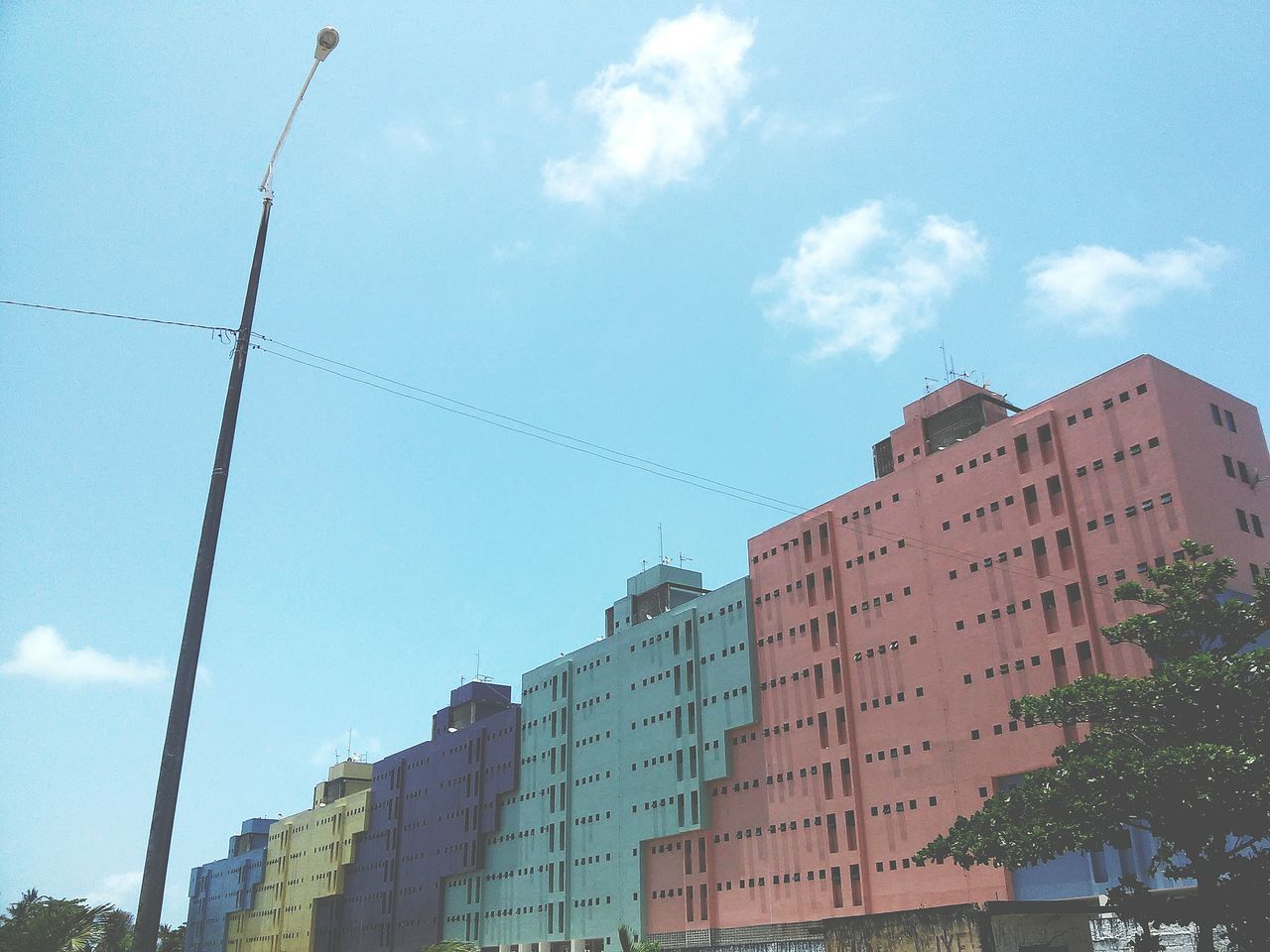 building exterior, architecture, built structure, low angle view, sky, building, blue, city, residential building, residential structure, day, cloud, outdoors, no people, cloud - sky, tree, window, house, street light, sunlight