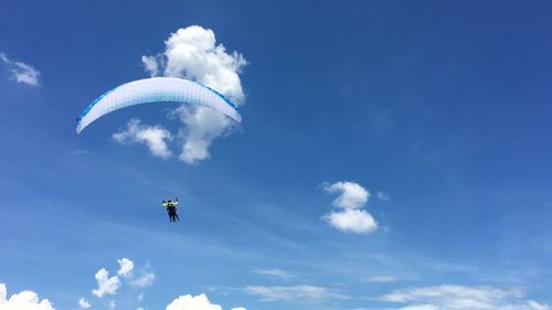 Low angle view of person paragliding against blue sky