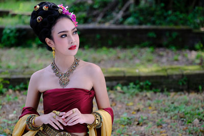 Beautiful young woman wearing traditional clothing and jewelries while standing on field