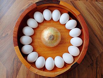 Directly above shot of eggs and onion in wooden container on table