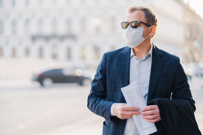 Businessman wearing mask while standing in city