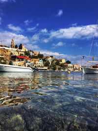 Boats moored at harbor in city against sky