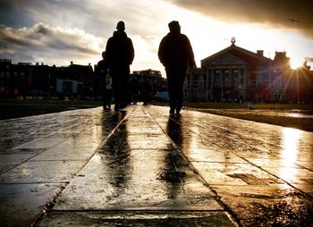 Silhouette men in city against sky during sunset