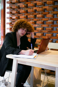 Portrait of young woman using laptop at cafe