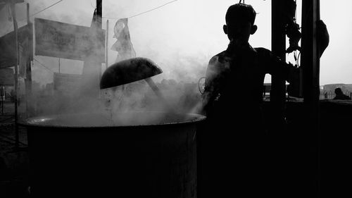 Rear view of silhouette woman standing in kitchen