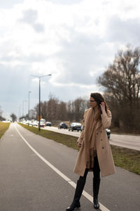 Full length of woman standing on road against sky