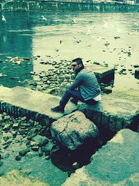 Man sitting on rock at beach