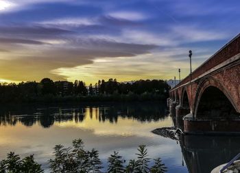 Bridge over river against sky during sunset