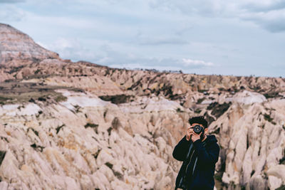 Man photographing with camera while standing against sky