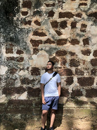 Full length of young man standing against wall